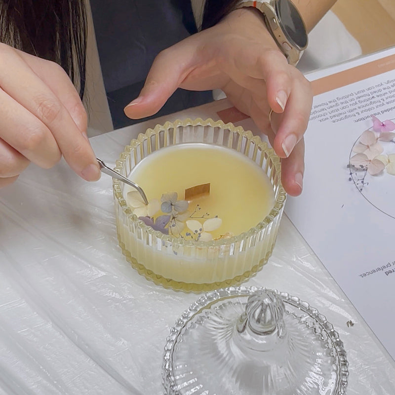 A guest carefully decorating a candle with delicate dried flowers